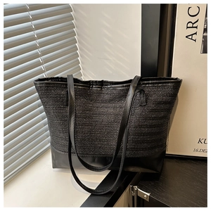 Detail of black woven tote bag showing herringbone texture and smooth leather base