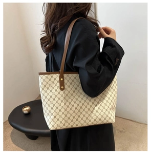 Détail du sac cabas beige vintage avec motifs de chaîne et lanières en cuir sur modèle