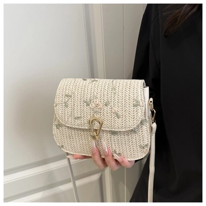 Close-up of woven straw bag with floral embroidery and golden horseshoe lock detail