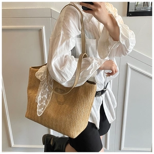 Detail of V-shaped straw weave pattern and white lace bow on a large tote bag
