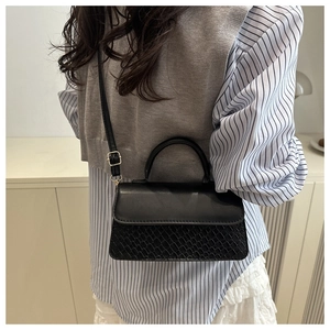 Detailed shot of black woven leather handbag with adjustable strap and gold hardware