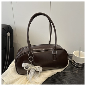 Deep brown glossy shoulder bag with white pearl lace bow charm on a soft fabric background