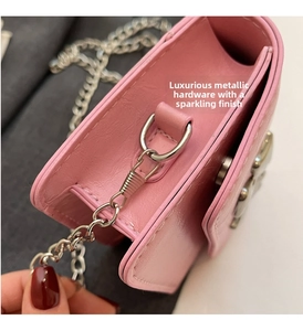 Detail view of pink textured leather crossbody bag with silver chain strap and stitching