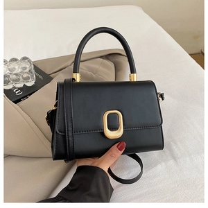 Close-up of black leather crossbody bag with elegant gold oval lock and top handle
