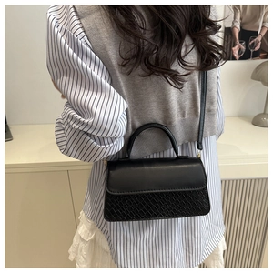 Detail of black crossbody bag featuring textured woven panels and elegant gold hardware
