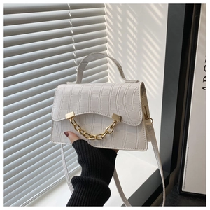 Detail of white crocodile-embossed mini bag with signature chunky gold chain decoration