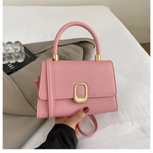 Detail of the elegant pink leather handbag with a textured gold metal buckle and top handle