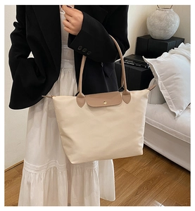 Détail du cabas en nylon crème avec anses en cuir marron et fermoir à pression doré