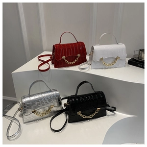 Four textured crossbody bags in red, white, silver, and black with gold chain details