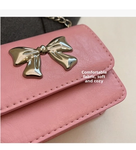 Detail of pink pebbled leather mini bag featuring a silver bow and metal chain strap