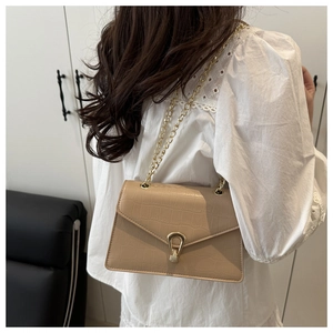 Detail of light khaki crossbody bag with crocodile texture and gold chain strap