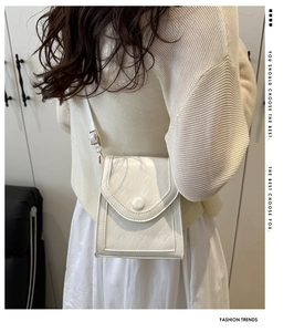 Detail of white quilted crossbody bag with metal buckle and adjustable shoulder strap