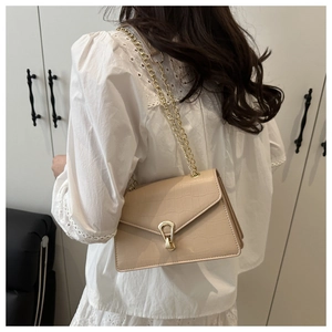 Close-up of beige crocodile pattern handbag featuring a gold chain and metal buckle