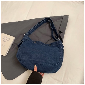 Détail du sac bandoulière en denim bleu avec coutures blanches et bouton en métal