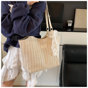 Detail of woven straw tote bag with lace bow decoration and premium leather logo tag