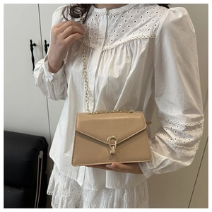 Detail of beige crocodile embossed leather bag with gold chain and metal clasp buckle