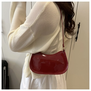Sac sous le bras en similicuir rouge brillant porté par un mannequin chic