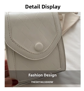 Close-up of white crossbody bag featuring quilted rhombus pattern and magnetic button