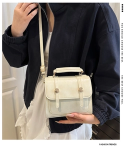 Close-up of beige PU leather handbag with dual vertical straps and round metal rivets