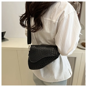 Detail of black woven saddle bag texture with adjustable wide strap for women