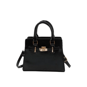 Glossy black trapezoid handbag with gold hardware and adjustable crossbody strap