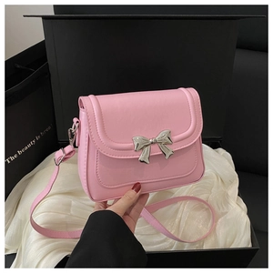 Detail of pink bow handbag featuring a silver metal buckle inside a luxury gift box