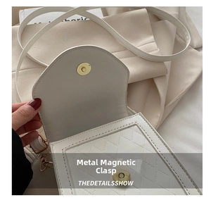 Detail view of the gold magnetic snap closure on a white quilted crossbody phone bag