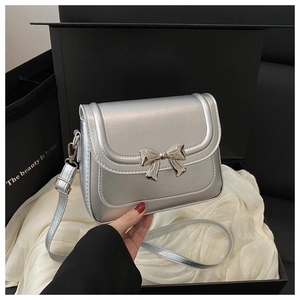 Close-up of metallic silver bow buckle and pearlescent texture on small crossbody bag