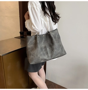 Detail view of large charcoal tote bag with vintage texture and metallic chain straps