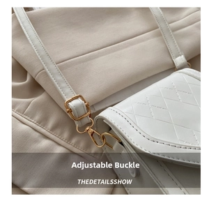 Detailed close-up of the metal adjustment buckle and leather strap on a white quilted bag