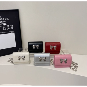 Close-up of mini crossbody bags in five colors with metallic bow clasps and chain straps