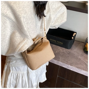 Detail of light brown woven texture bag with stylish metal chain strap and zip closure