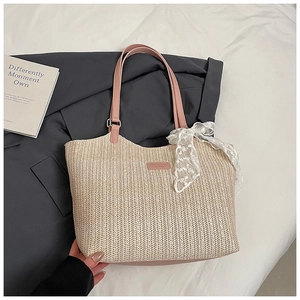 Detail of straw woven tote with pink leather handles and delicate lace bow accent