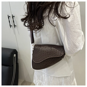 Detail of dark brown woven saddle bag texture with elegant gold hardware accents