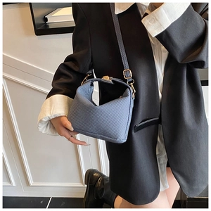 Detail of blue woven texture hobo bag with gold metal clasp on black blazer