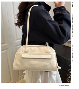 Elegante borsa da bowling in pelle bianco crema indossata a spalla da una modella di moda