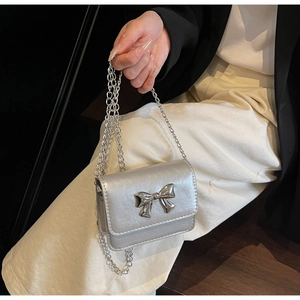 Detailed macro view of the silver mini bag featuring a chic metal bow and chain strap