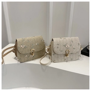Detail of floral embroidery and gold teardrop clasp on woven crossbody bags