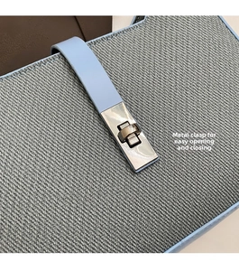 Detalle del cierre de metal plateado en bolso de lona gris texturizada y cuero azul