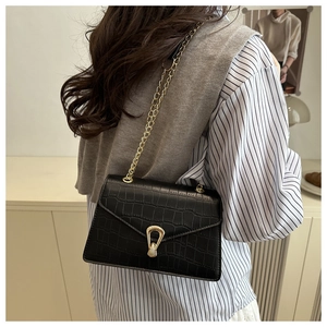 Detail of black faux crocodile pattern leather bag with golden chain and stylish metal lock