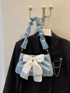 Detail of light blue handbag featuring a large white bow and cloud-style pleated handle