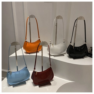 Cinq sacs à bandoulière en cuir verni brillant présentés sur des supports argentés