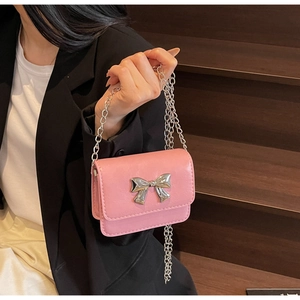 Detailed close-up of a bright pink mini crossbody bag with a silver metal bow buckle