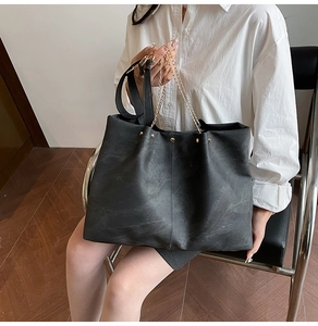 Modell mit großer schwarzer Soft-Leder-Tote-Bag mit goldener Kette und Nietendetails