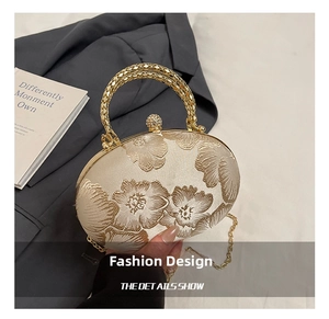 Detailed macro view of 3D floral embroidery and golden metal handle on the beige clutch bag