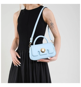 Detail of light blue rectangle leather handbag with gold round buckle and adjustable strap