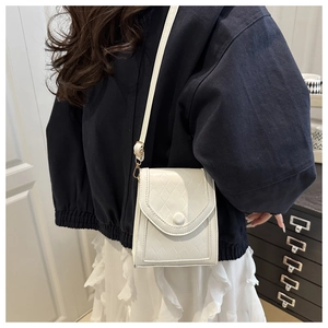 Close-up of white quilted crossbody bag with rhombic stitching and flap closure