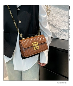 Detail of quilted brown patent leather crossbody bag with golden H-lock and chain strap