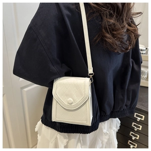 Detailed side view of a white quilted mini crossbody bag with gold hardware on a model