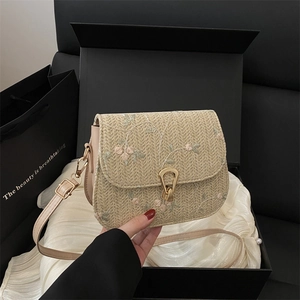 Floral embroidered straw crossbody bag with gold lock buckle and cream woven texture